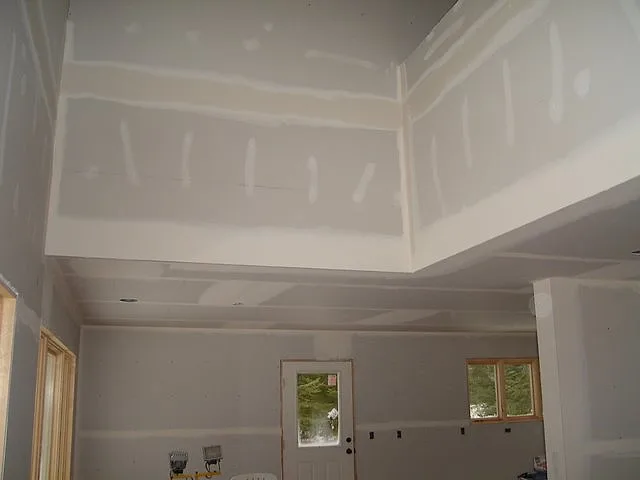 Kitchen space in a new home with taped drywall, an open soffit and a back door, before cabinets go in