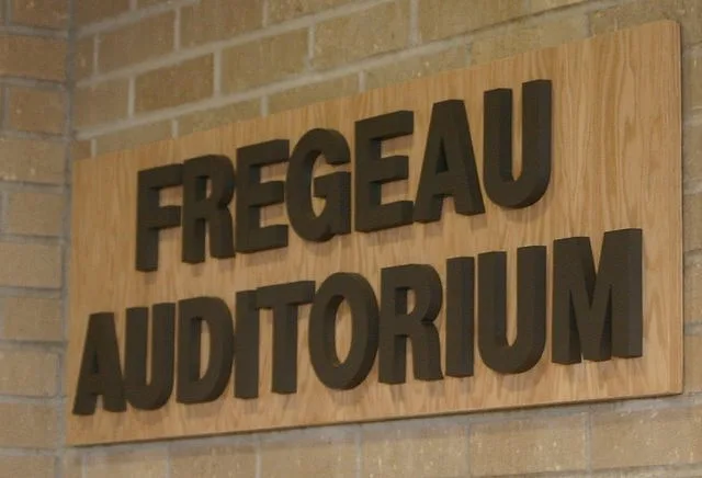 Raised wooden letters reading Fregeau Auditorium on a brick wall at Marshall School in Duluth, a J.A. Houle commercial job