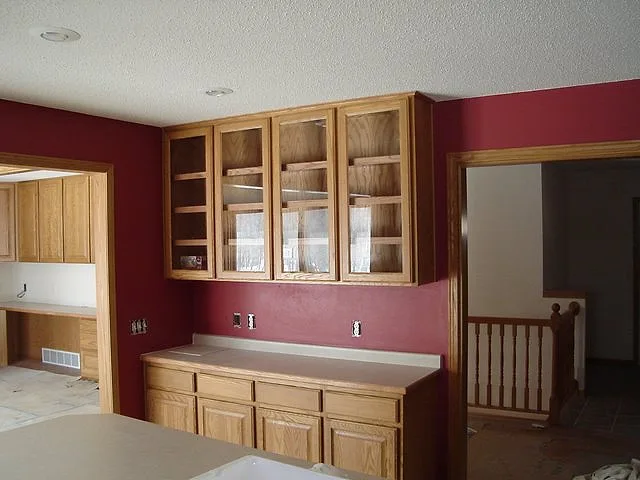 Kitchen with deep red painted walls, oak cabinets and glass-front uppers, freshly painted by J.A. Houle Painting